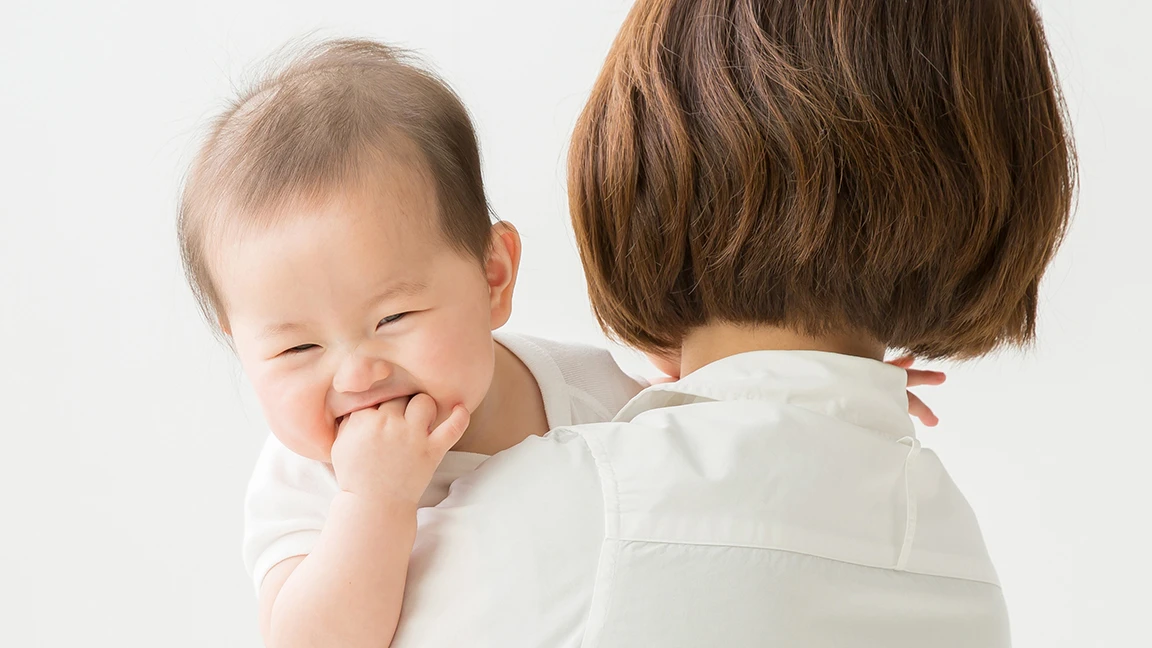 笑顔の赤ちゃんを抱いて見つめる母親の写真