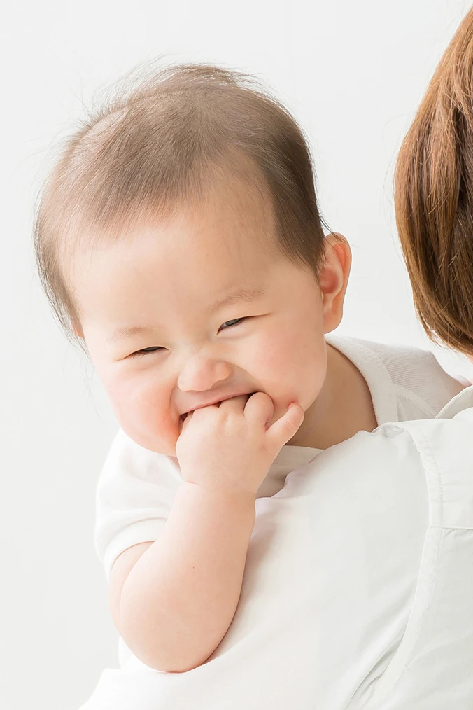 笑顔の赤ちゃんを抱いて見つめる母親の写真